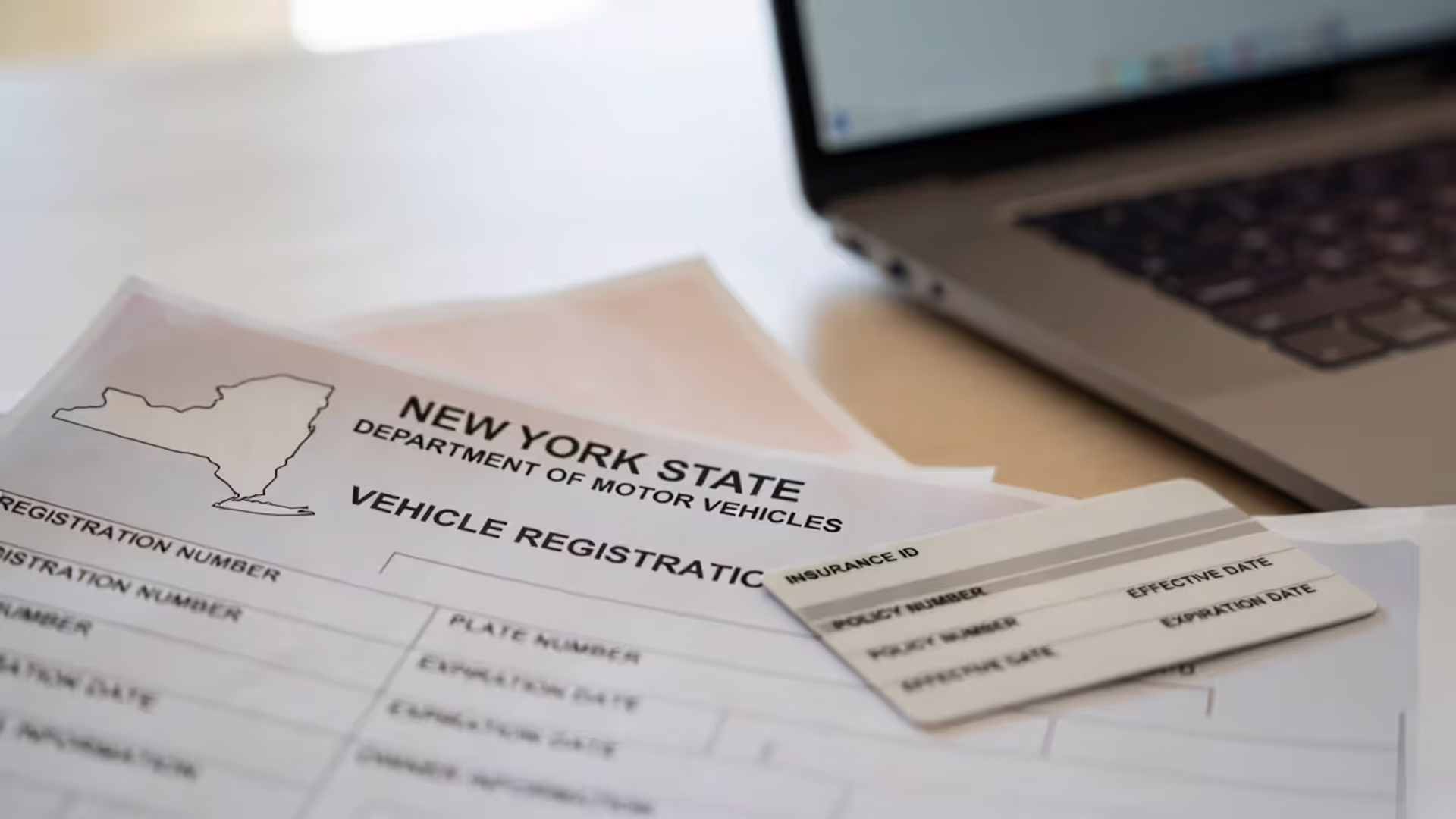 New York registration paperwork next to a generic insurance card on a desk.