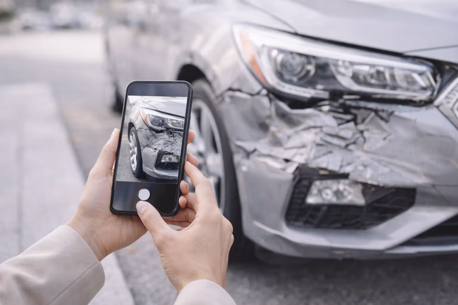 person taking photos of damaged car for insurance claim
